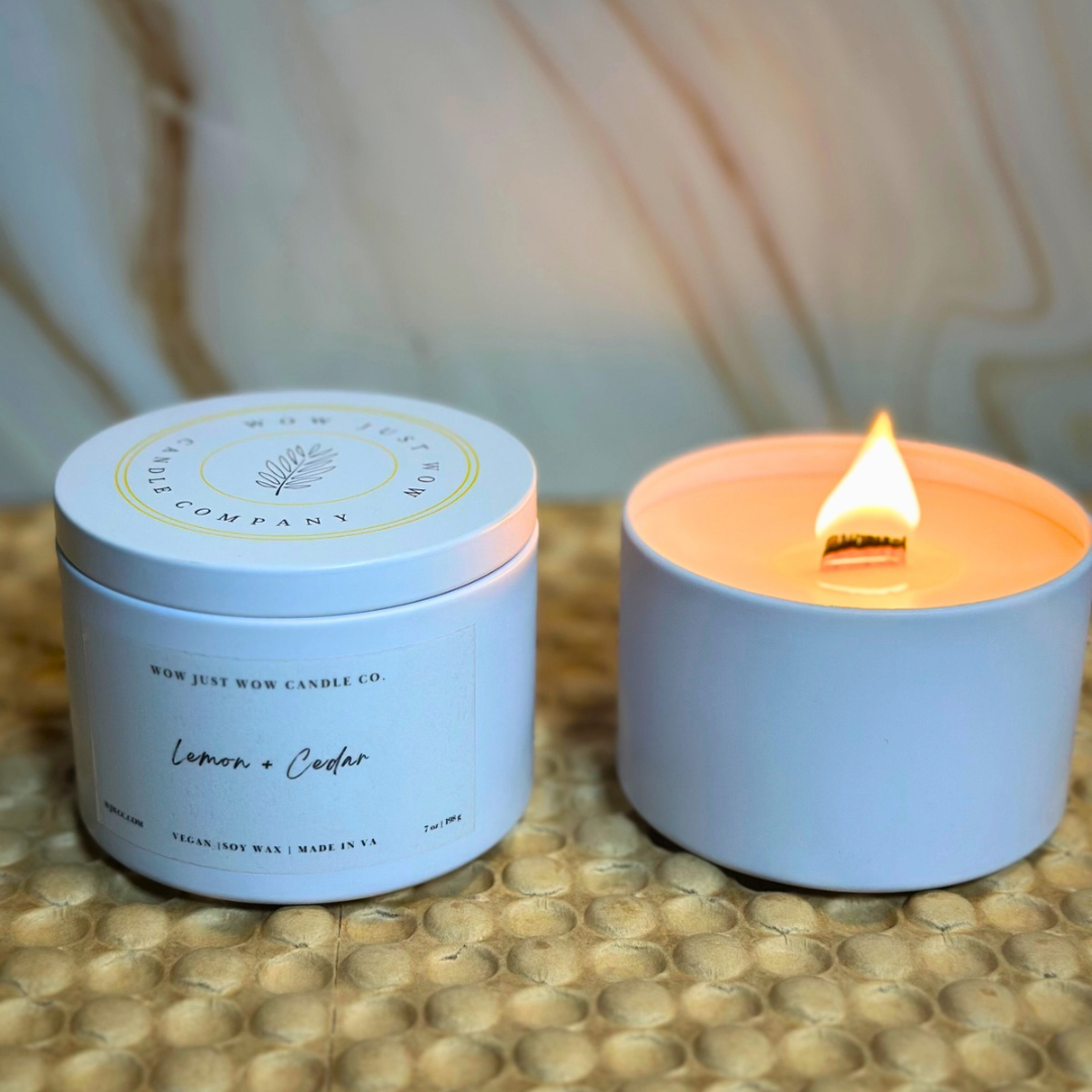 Soy candle in light-blue jar, flame on top; matching lid labeled Lemon + Cedar