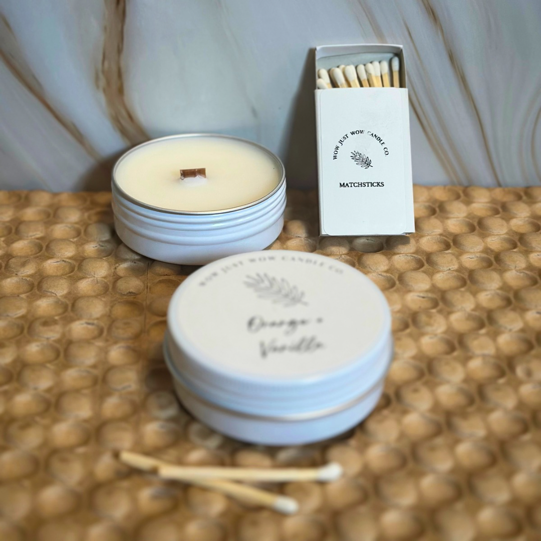 Stacked light blue candle tins with orange vanilla label, with matchbox and matches