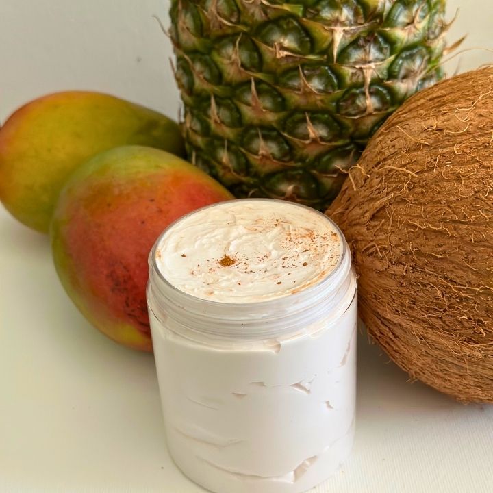 Whipped Body Butter: Rich and creamy whipped body butter for intense moisture and soft skin. A jar of creamy whipped body butter next to a gold-colored spoon, both with a white creamy product on them, on a light background.