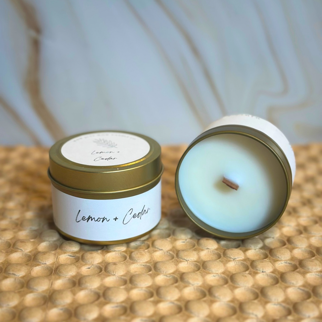 Soy candle jar with gold lid and Lemon + Cedar label; nearby jar with visible wick