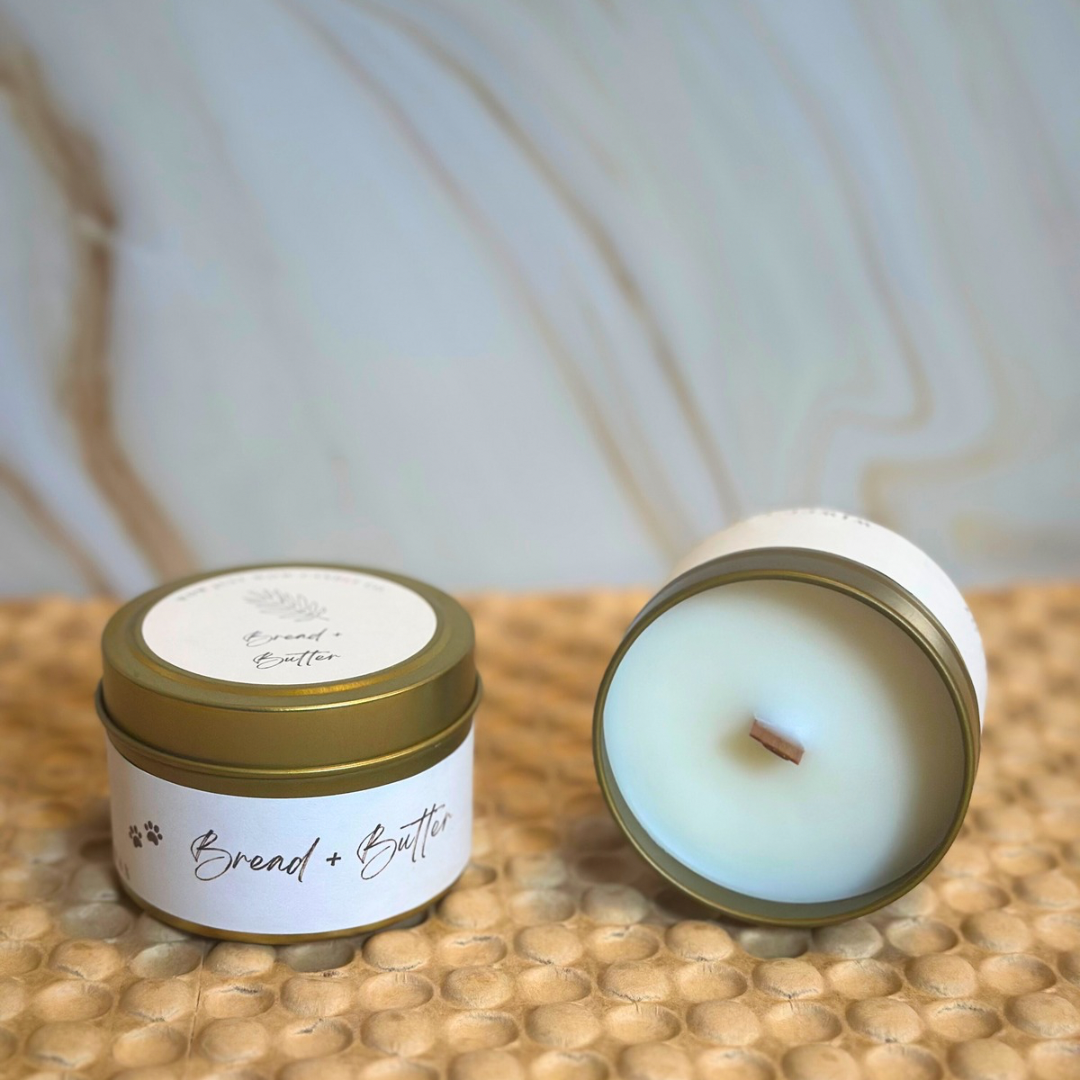 Two soy candles on tabletop: open lid shows white wax and wick in gold container