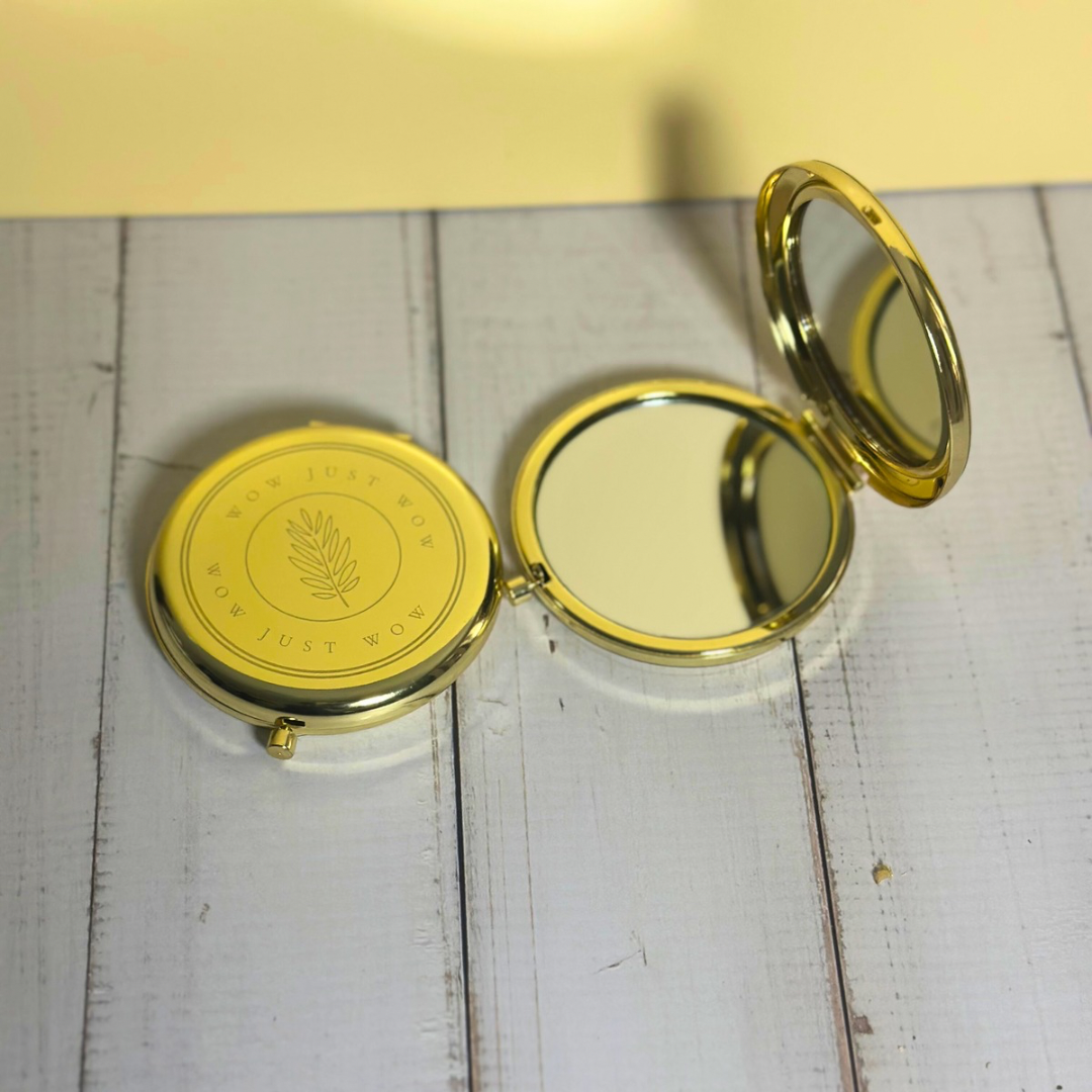 Gold compact mirror on a white wooden surface