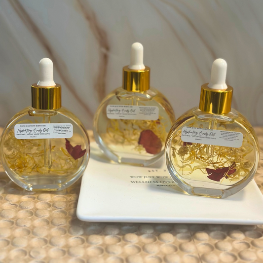 Three bottles of body oil with droppers on a textured surface. Hydrating Body Oil (Bali Mango): Hydrating Bali Mango body oil infused with 24k gold flakes for glowing, radiant skin.
