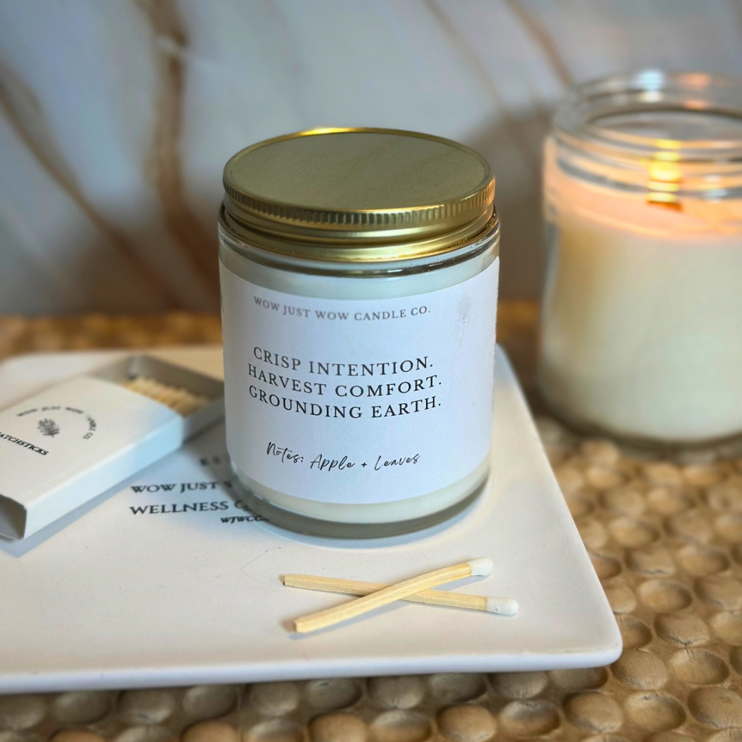 Candle jar with a label on a tray with matches, next to another candle.