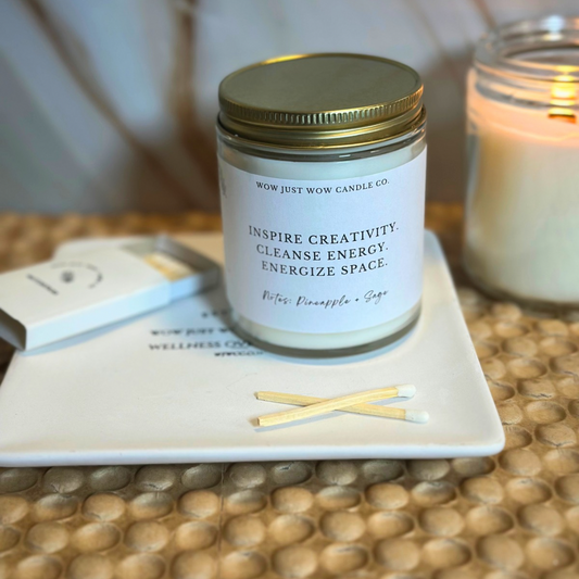 Candle jar with a label on a coaster with matches, on a textured surface.