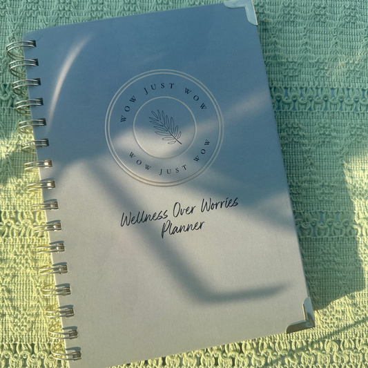 Planner with 'Wellness Over Worries' text on a textured green surface