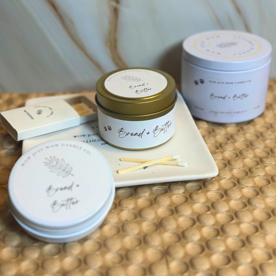 Assorted soy candle tins on tray: gold and light blue containers with matchsticks